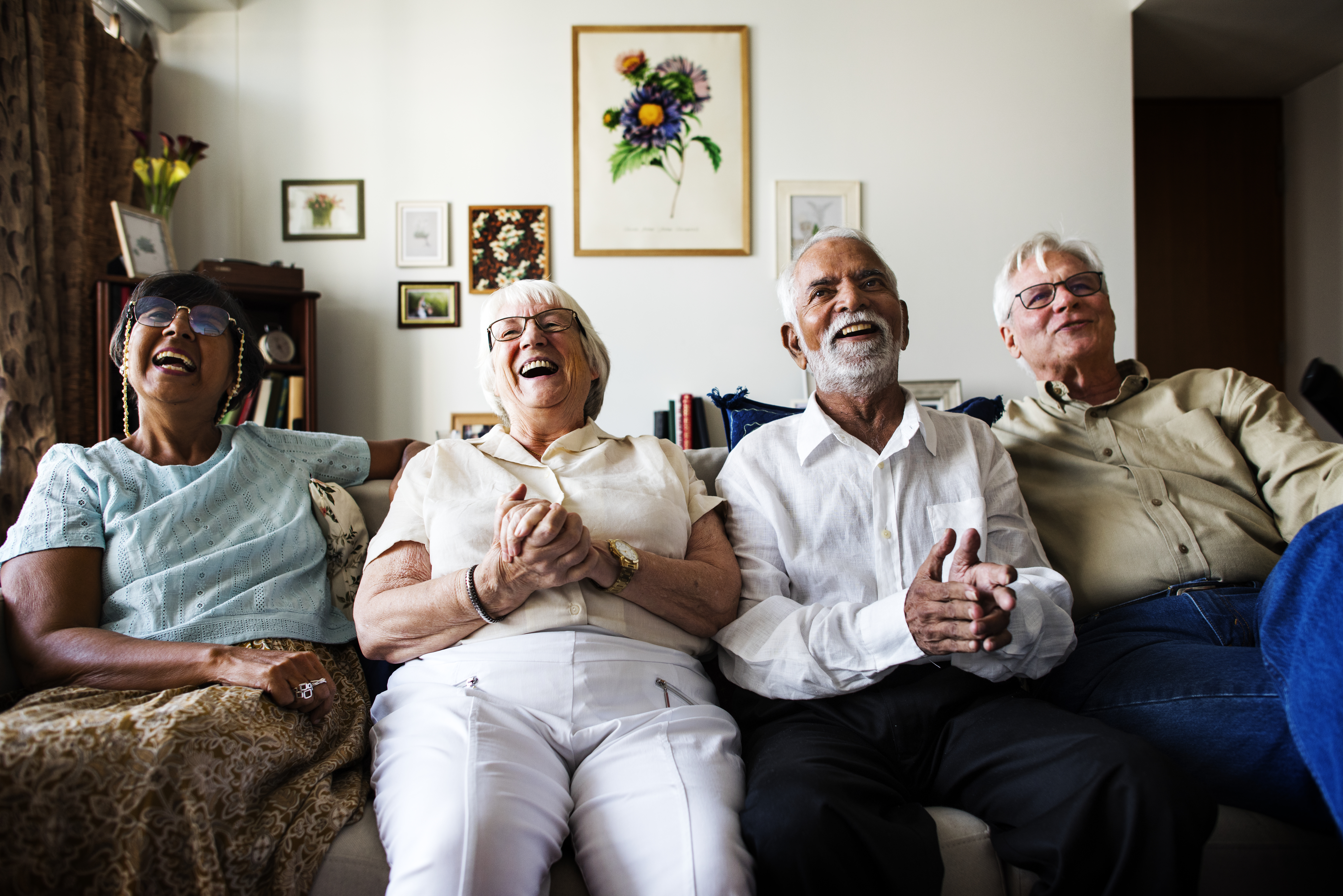 Diverse group of older adults sitting on a couch and laughing.