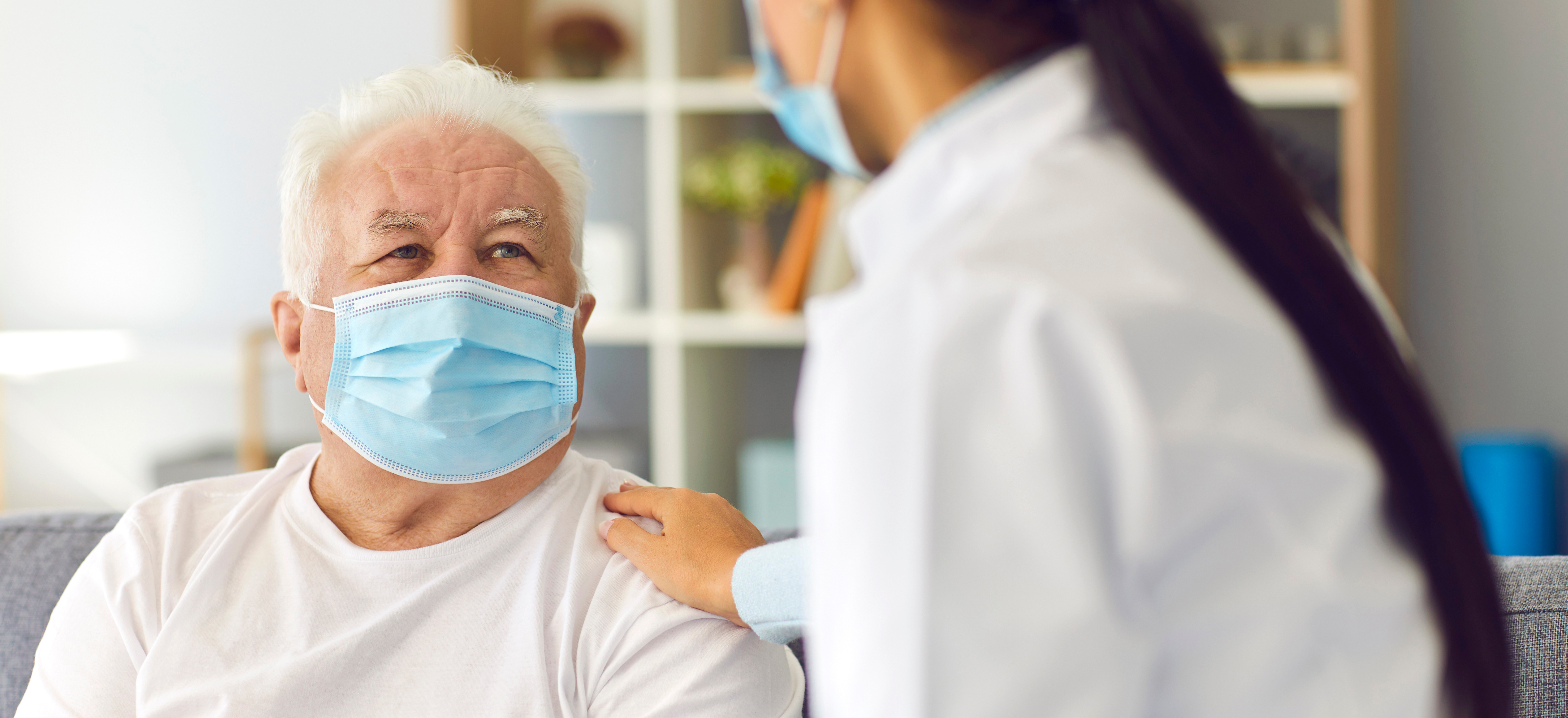Doctor visiting senior patient at home during period of seasonal infection or Covid 19 pandemic