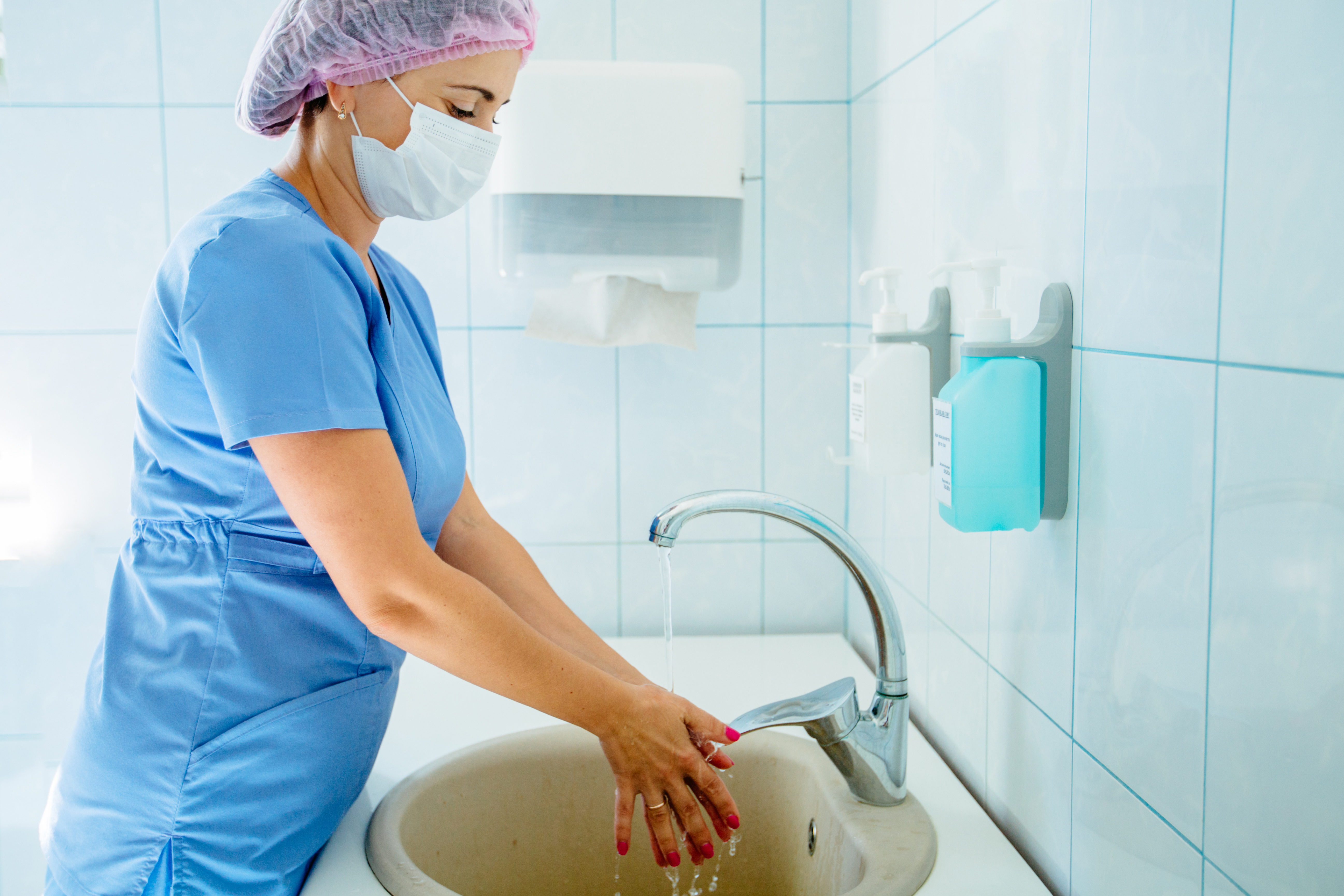 Female doctor gynecologist washing hands before or after operation in light operating theatre.
