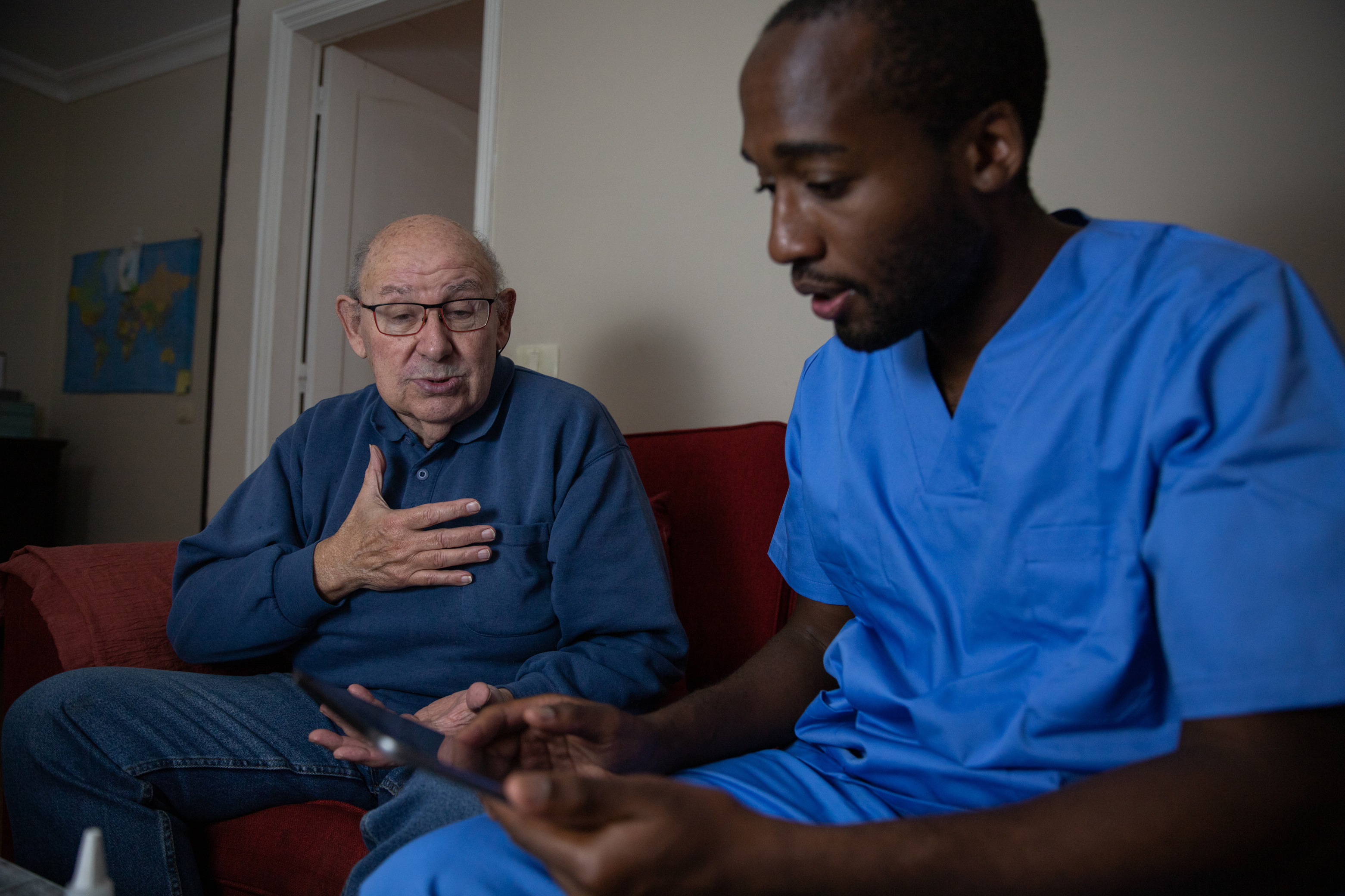 An elderly patient talks to medical professional during a home doctor visit.