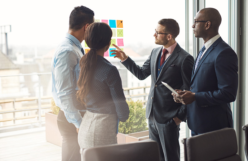 Image of healthcare executives brainstorming in front of sticky notes adhered to a glass window.