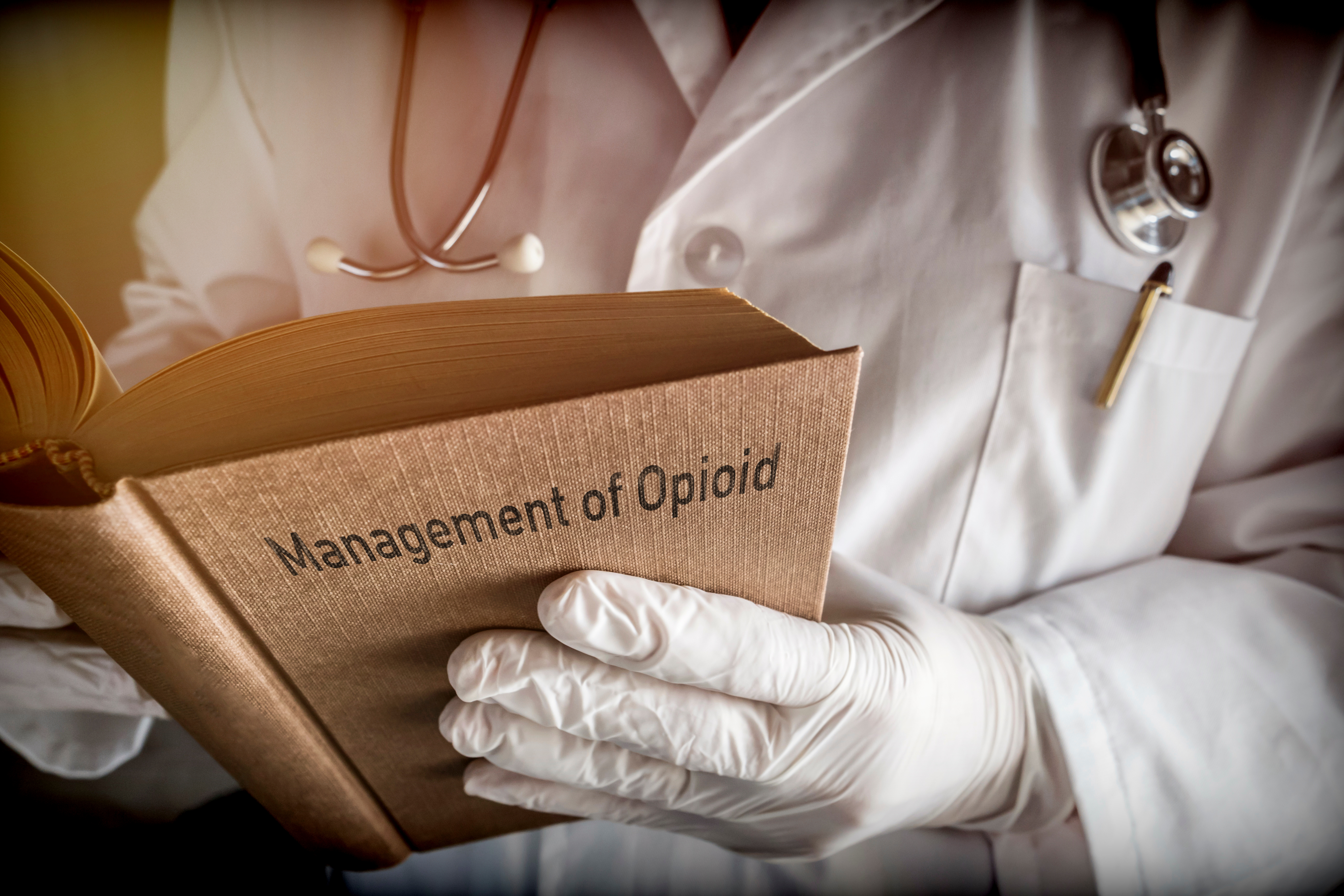 Doctor holds book on Management of Opioid, conceptual image