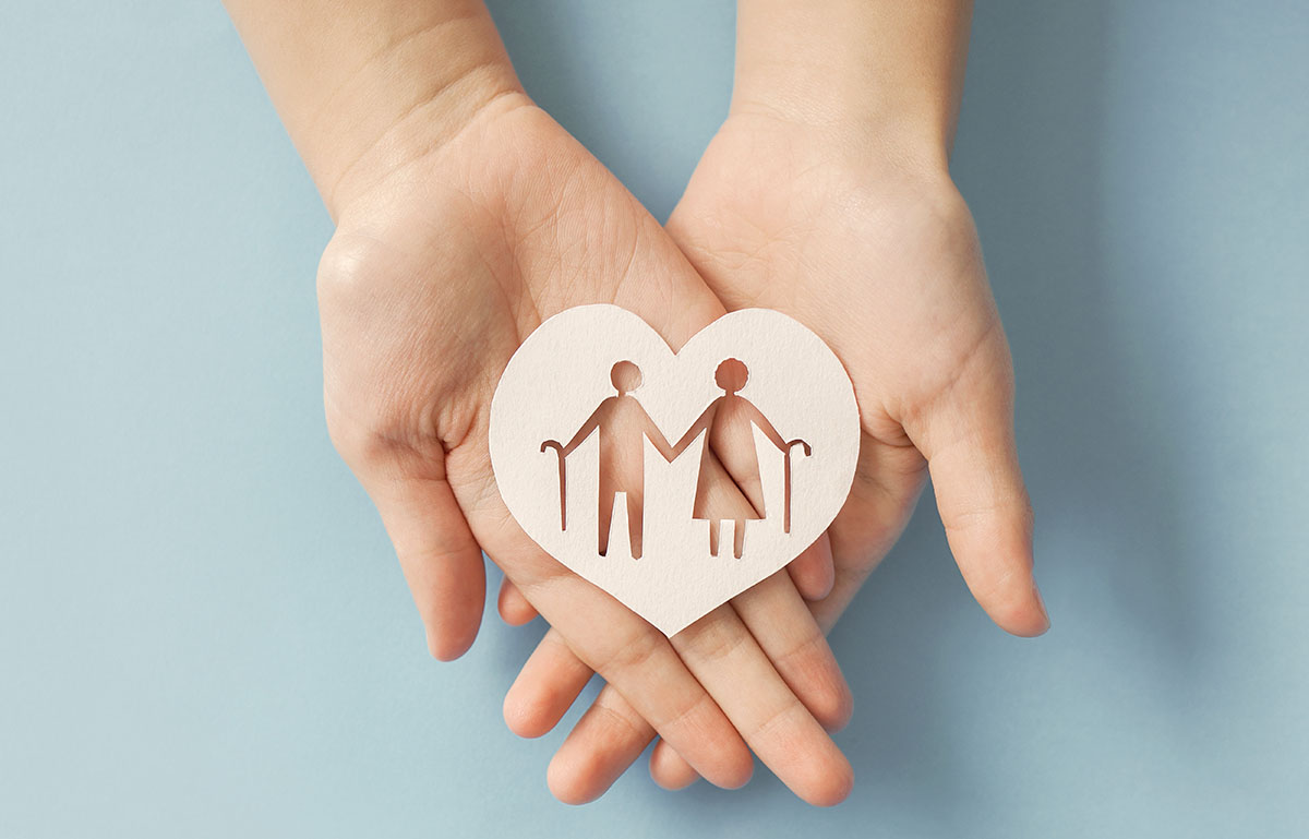 Hands holding a heart with elderly cutouts