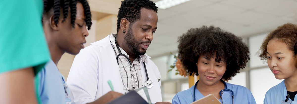 Group of African American doctors looking at clip boards.