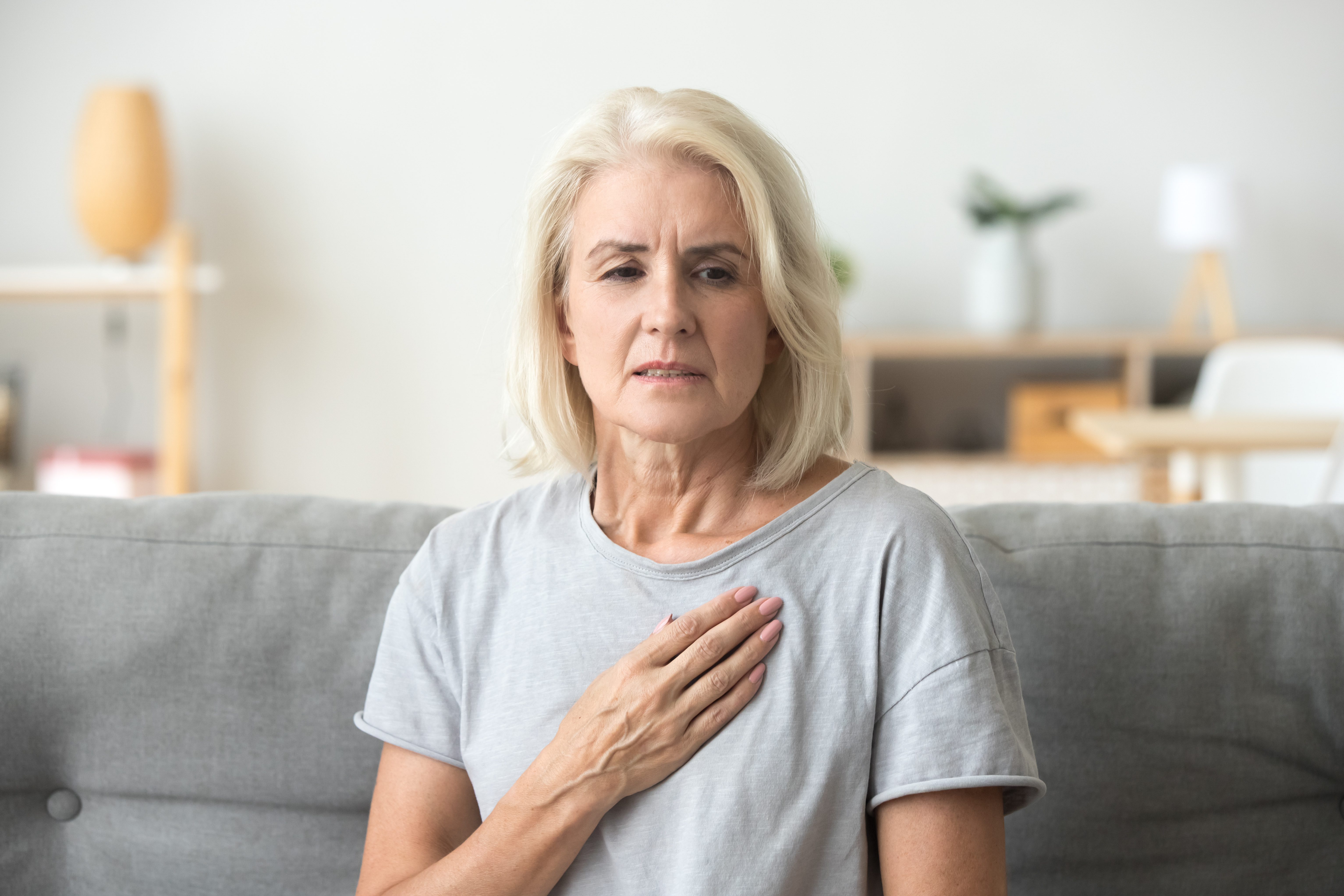 Upset stressed mature older woman feeling heartache touching chest