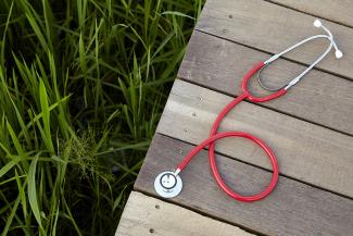 Image of a red stethoscope on a wood boardwalk.