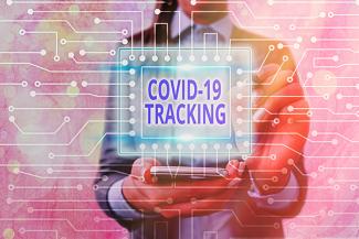 Photo of person holding a COVID-19 Tracking sign