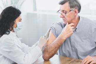 Nurse administering vaccine to senior patient