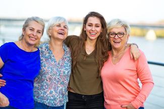 Two mothers and daughters standing together smiling