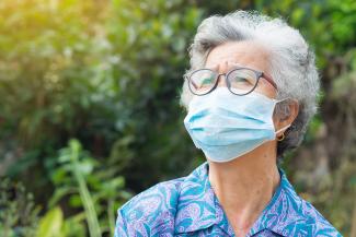 Portrait of elderly woman with short white hair, wearing face mask for health because have air pollution. Mask for protect virus, bacteria, pollen grains. Health care concept
