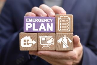 Person holding wooden blocks with different icons and the words emergency plan