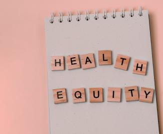 Message health equity with wooden letters on notebook with pink background