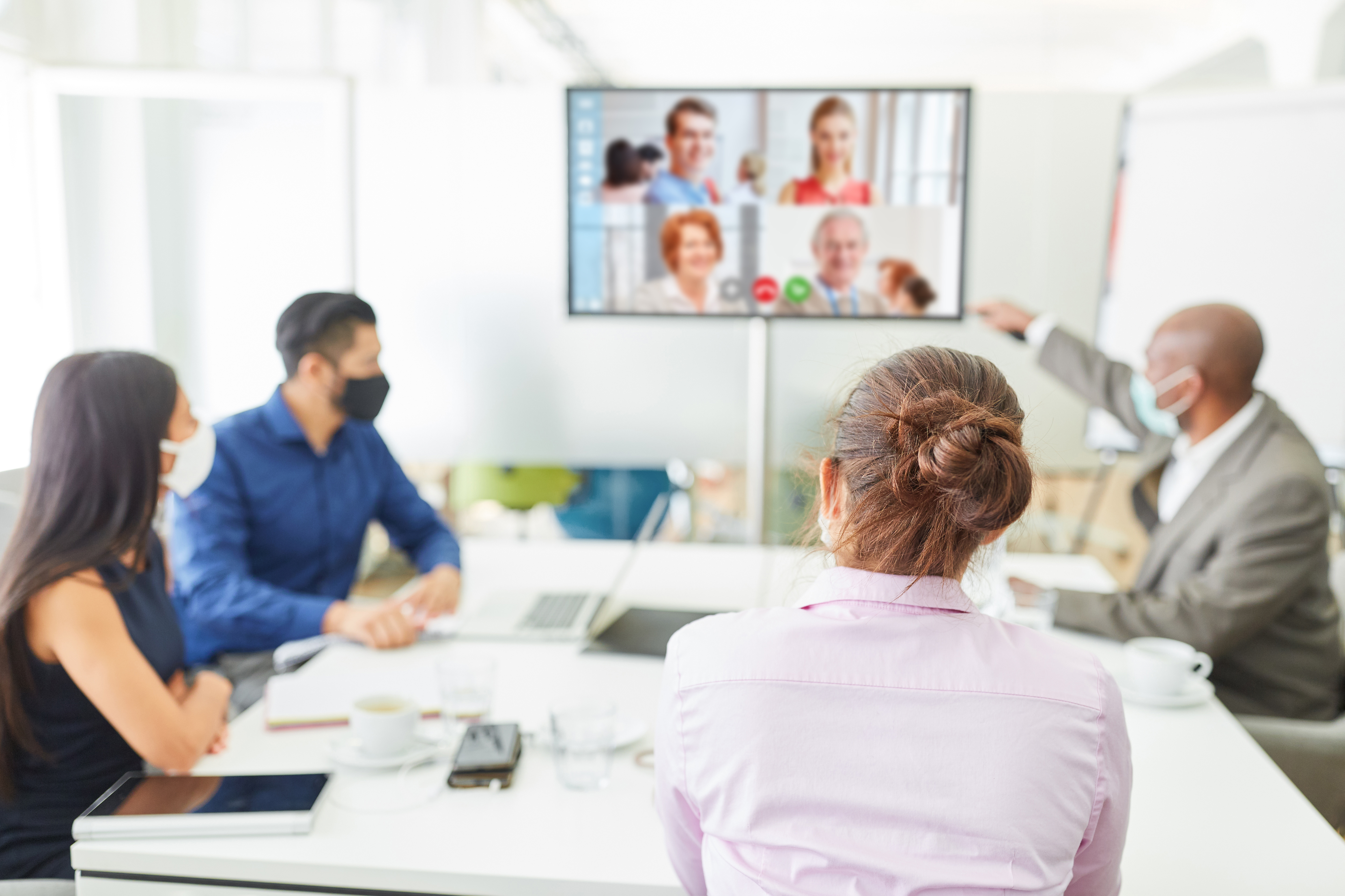 Staff in conference room attending a virtual meeting with additional staff