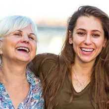 Two mothers and daughters standing together smiling