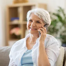 Image of older woman holding a cell phone to her left ear and smiling.