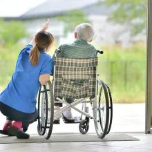 Nurse and patient, in wheelchair, looking outside to nature.
