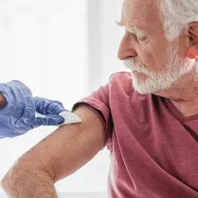 Elderly man getting vaccinated by clinician