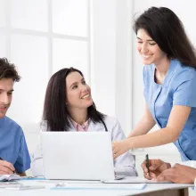 Practitioners and interns discussing medical reports on laptop