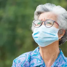 Portrait of elderly woman with short white hair, wearing face mask for health because have air pollution PM 2.5. Mask for protect virus, bacteria, pollen grains. Health care concept