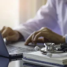 Stethoscope on prescription clipboard and Doctor working an Laptop on desk in hospital, Healthcare and medical concept, vintage color, selective focus.