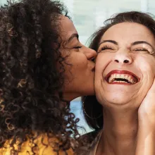 happy latin american family. curly-haired daughter kissing her mother