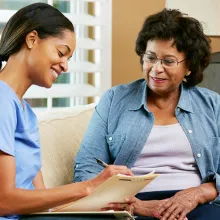 Female healthcare worker filling in a form with a senior woman during a home health visit