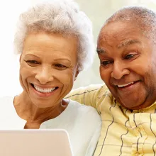 Male and female elder looking at laptop while sitting on couch