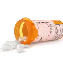 Image of white pills spilling out of a prescription bottle