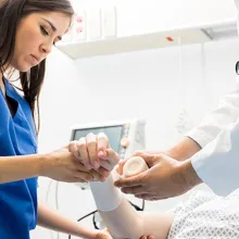 Female nurse and male nurse assisting elderly patient in hospital bed