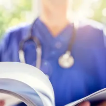 Female provider reading through pages on a clipboard standing outside