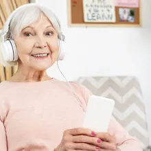 Elderly woman with headphones on sitting on couch