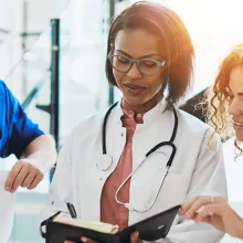 Two females and one male hospital staff in a discussion and looking at a document.