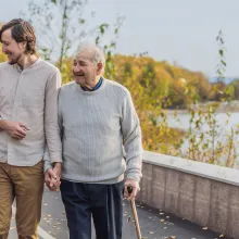 An elderly couple walks in the park with a male assistant or adult grandson. Caring for the elderly, volunteering.