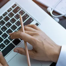 Subject at laptop holding pencil