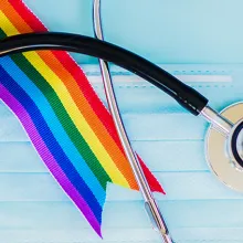 Stethoscope and LGBT rainbow flag pride symbol and medical mask. Blue background