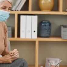 Female nurse speaking with female patient with mask on