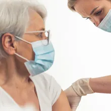 Female nurse giving female elderly patient a vaccination