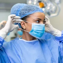Portrait of female doctor surgeon putting on medical mask standing in operation room. Surgeon at modern operating room