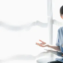 Asian nurse speaking to female patient with clipboard in her hand