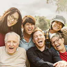 Happy multigenerational people having fun sitting on grass in a public park