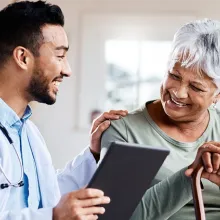 Male provider and female elderly patient sitting next to each other smiling