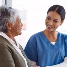 Caregiver with senior woman and holding hands for care indoors