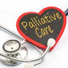 Image of a wooden shaped heart with the words  'Palliative Care' written on it next to a stethoscope.