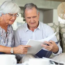 Elder couple reading papers together on a sofa