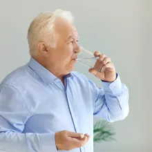 Elderly man drinking water with medication in his hand