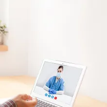 Senior male speaking with a healthcare provide via a laptop.