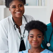 Three female healthcare workers smiling at the camera.