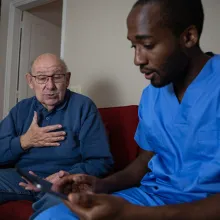 An elderly patient talks to medical professional during a home doctor visit.