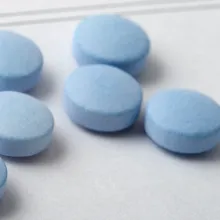 Round Blue Pills Spread Out on a Blank Prescription Form.