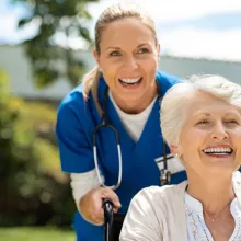 Clinician walking elderly person in wheelchair